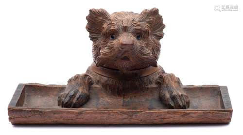 A Black Forest carved linden wood inkwell: in the form of a terrier dog holding onto a log ,