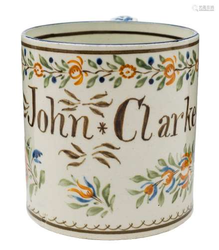 A Bovey Tracey pearlware mug: inscribed 'John Clarke' and decorated in blue, brown,