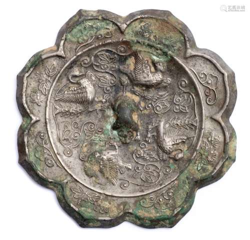 A Chinese silvered bronze mirror: of foliate eight lobed form, cast with birds, flowers and foliage,