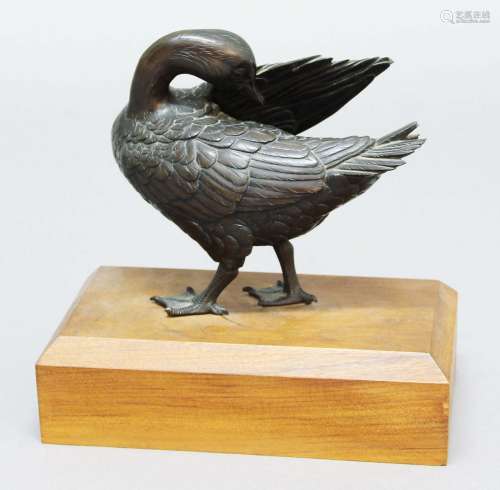 Japanese bronze duck,20th century, preening with one wing raised, on a mahogany