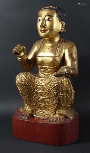 South east asian carved and giltwood female deity,modelled seated with one hand