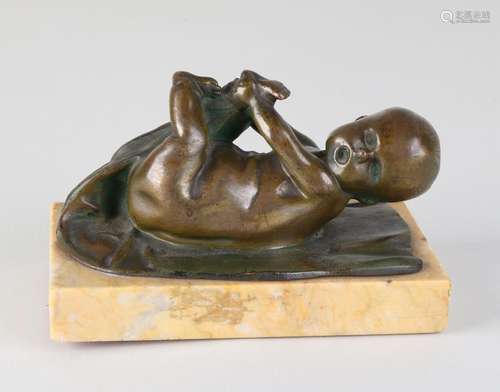 Antique bronze baby on marble basement. Circa 1920.