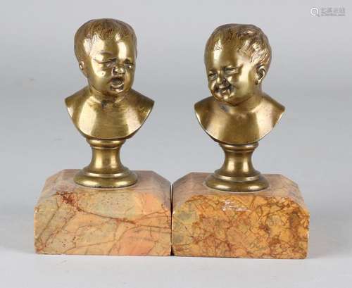 Two antique bronze children's busts on marble basement.