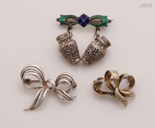 Three silver brooches, two in the form of a bow and a