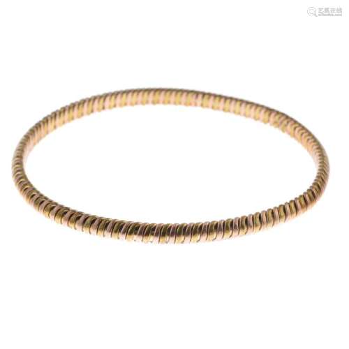 A 9ct gold bangle. Designed as a bi-colour grooved