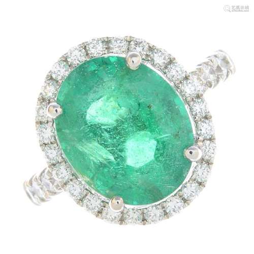 An emerald and diamond cluster ring. The oval-shape