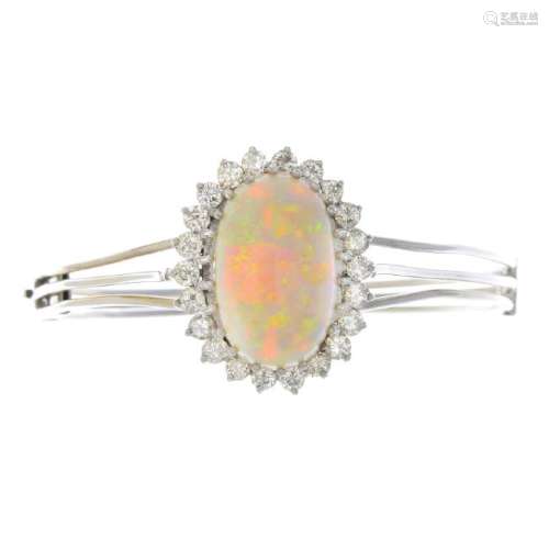 An opal and diamond hinged bangle. The oval opal