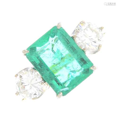 An emerald and diamond three-stone ring. The