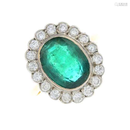 An emerald and diamond cluster ring. The oval-shape