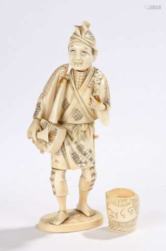 Japanese Meiji period ivory figure of a street musician, the musician carrying a bag and a