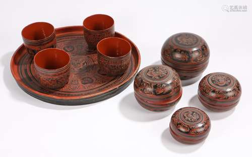 Nine Burmese lacquer items to include four graduated lidded bowls, four beakers and a tray decorated