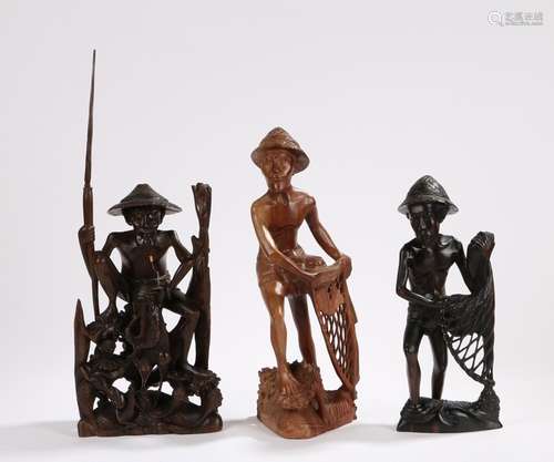 Three Burmese wood figures, carved as a fisherman with rod and fish, together with two figures