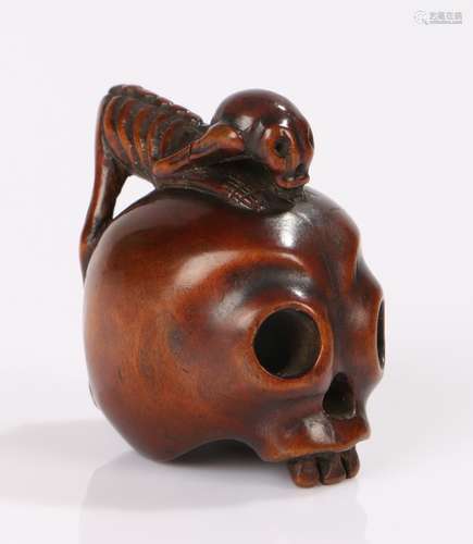 Japanese Meiji period netsuke, the box wood netsuke carved as a skull with a crawling skeleton,