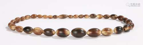 Graduated string of thirty-three oval beads, possibly rhinoceros horn, with screw clasp, 61cm