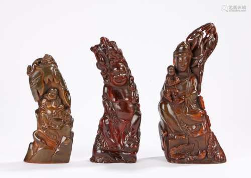 Three polished horn carvings depicting a mother and child and two smiling gentlemen, the largest