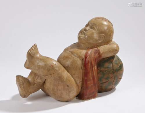 Wooden carving depicting the young Buddha wearing a red jacket, reclining on a watermelon, 35cm