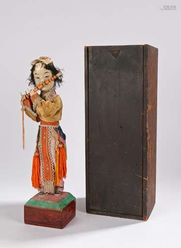 Chinese Republic figure of a boy playing a flute, richly dressed in silk with tassels and beads,