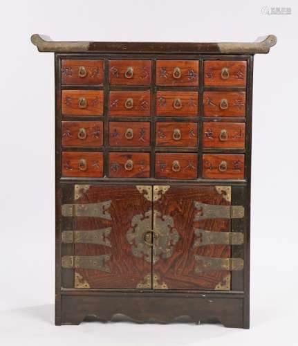 An Oriental table cabinet, with an arched top above a series of small drawers and cupboard below,