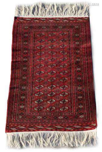 Property of a deceased estate - an Afghan Turkoman hand knotted wool rug with burgundy ground, 61 by