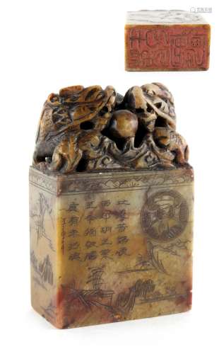 A Chinese carved soapstone seal, engraved with calligraphy & a landscape, the finial carved with two