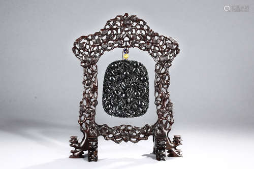 A BLACK JADE CARVED HANGING PLAQUE WITH CARVED WOODEN FRAME