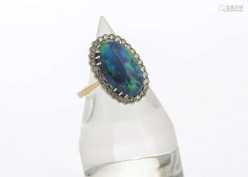 A contemporary diamond and black opal 18ct gold dress ring, the oval cabochon cut black opal in