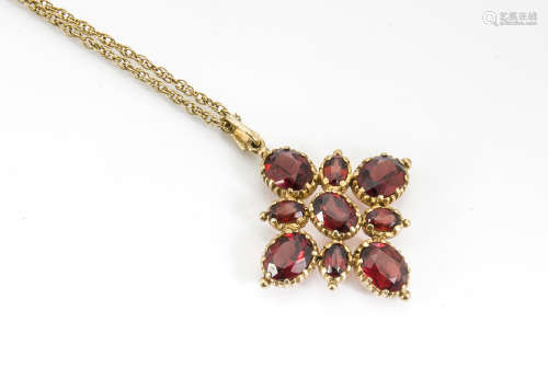 A 9ct gold garnet cluster pendant, the oval mixed cut stones within a cruciform style cluster in