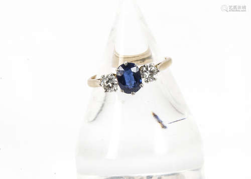 An Art Deco period sapphire and diamond three stone ring, oval blue sapphire flanked by a pair of