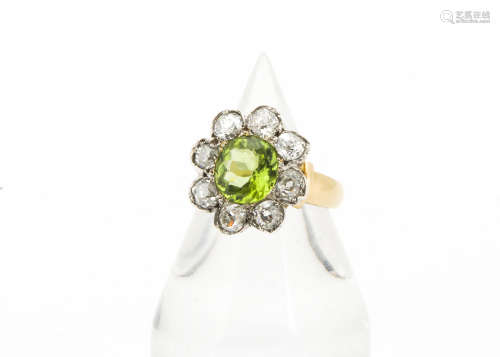 A peridot and diamond flower head ring, the circular mixed cut peridot surrounded by old cut