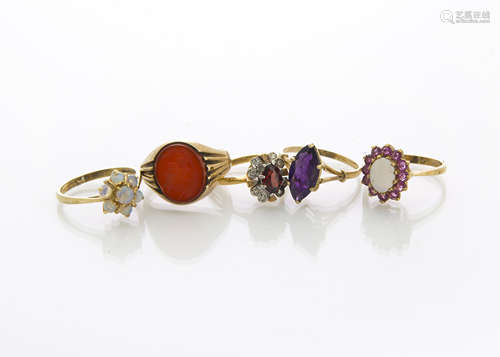 A collection of five gold rings, including two white opal cluster rings, a garnet and diamond