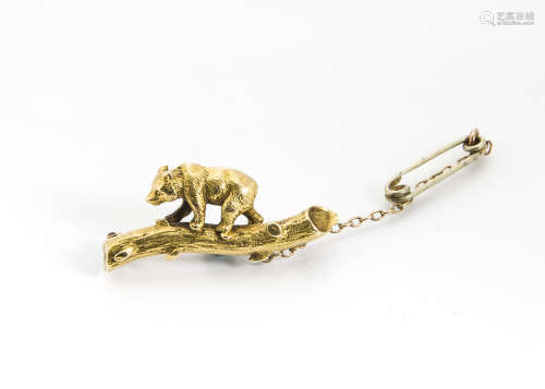 An early 20th Century yellow metal brooch, modelled as a bear on a log with engraved decoration,