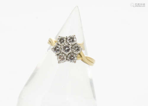 An 18ct gold diamond set flower head cluster ring, the seven claw set brilliant cuts in a white gold