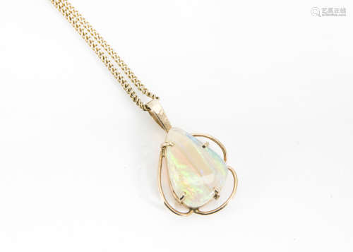 A white opal drop pendant, the pebble shaped stone in a four claw setting marked 9K on a curb link
