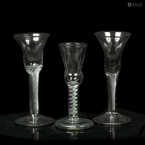 Two bell shaped wine glasses each with spiral air twist stems and a single thistle shaped glass with