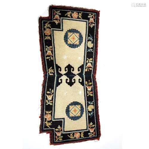 Chinese saddle rug ivory ground with black foliate banded border, 136cm x 59cm