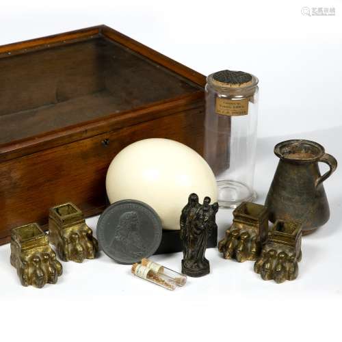 A glass cabinet with a group of objects comprising four ormolu lion's paw feet, 19th Century, a