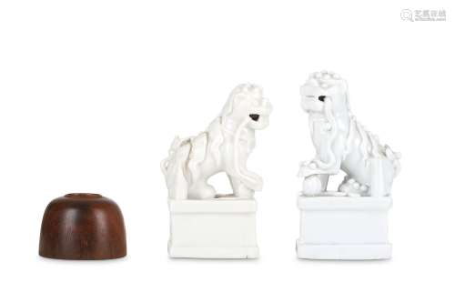 TWO BLANC-DE-CHINE LION DOGS JOSS STICK HOLDERS. 19th Century. Each supporting his paw on a
