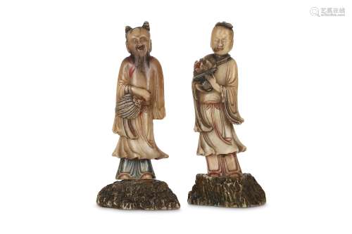 TWO CHINESE SOAPSTONE FIGURES OF IMMORTALS. Early Qing Dynasty. Each standing on a rock-shaped base,