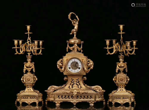 A GILT COPPER CLOCK WITH TWO CANDLESTICK
