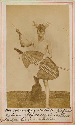 Albumen print carte-de-visite of a Zulu warrior posed with shield and spear, 85 x 50 mm laid down to larger card,  ZULU WARRIOR.