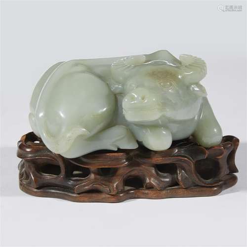 A Chinese carved celadon jade recumbent buffalo, on an associated wood stand