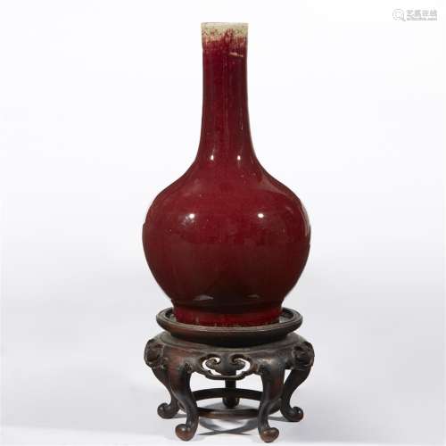 A Chinese copper red-glazed bottle vase with carved wood stand