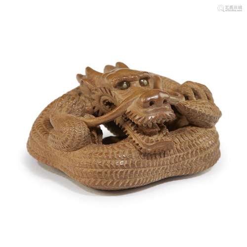 A Japanese carved boxwood netsuke of a coiled dragon, Tanetoshi