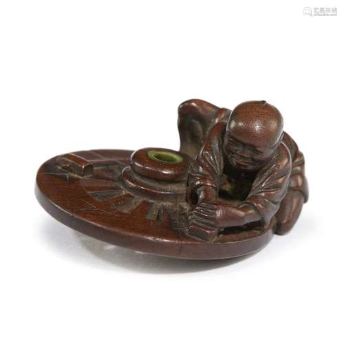 A Japanese carved dark wood netsuke depicting a man fixing a wagon wheel, Jugyoko