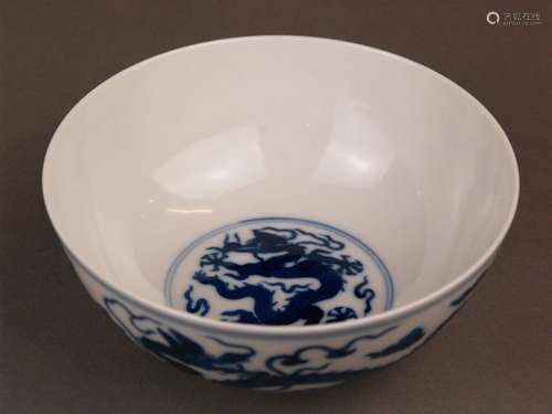 A Blue and White 'Dragon' Bowl - Mark of Guangxu, with deep rounded sides and a slightly<br />everted rim, supported on a narrow footring, painted around the exterior with two dragons striding among clouds and flames, double line borders encircling the rim and foot, the base inscribed in underglaze blue with a six-character reign mark, h.appr.6,5cm cm (2.5in.)/dm appr.15cm(5.9in.), slight vertical hairline crack to the body