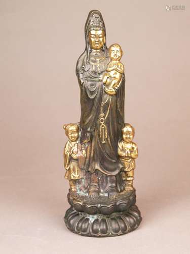 Songzi Guanyin - China, 20th century, yellow bronze patinated brown, partly polished, the<br />goddess capable of granting children, full figure of the Mother Goddess and the Goddess of Mercy standing on a double lotus pedestal, in the right arm she is holding a child, she is accompanied by the Shancai boy and the Longnü girl, stand with four-character mark, copper efflorescence, H.ca.26cm, ca.1520g