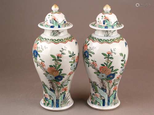 Pair of lidded vases - China, Republic-era, slim baluster shape with helmet lid,<br />Porcelain, painted in the Wucai color palette with flowering shrubs, butterflies, flowers and encircling Ruyi head boarders, lid knobs and flowers painted gold, knobs slightly rubbed, 1 lid visibly restored  on the rim, height ca.28 / 29cm, weight: ca.1348 / 1400g