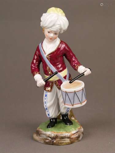 Musician from ''The Turkish Orchestra''- Hoechst, Germany, blue wheel mark with painter's<br />mark 'Tö 423', 20th century, drummer, porcelain, glazed, polychrome painted and gold-plated, red jacket, white trousers with blue pattern, black boots and white turban, on naturalistic base, designed by Johann Peter Melchior (1747-1825), H.ca.18cm