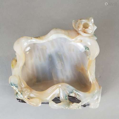 Finely Carved Agate Brush Washer- China, Qing dynasty, 19th century, translucent, smoky<br />agate with brown inclusions as well as others green and whitish mineral traces, finely carved dish of lotus leaf shape with curled edge  and incised veins, full round branches to be used as foot or handle, the exterior carved with a full round half open lotus flower, a dragonfly, a butterfly and a miniature duck, some chipping  f.e. to the butterfly antenna and wing, material-inherent cracks, partly restored, c.13x14cm / h. up to c.6.5cm