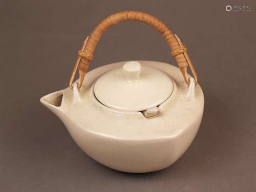 Teekanne - Japan, Keramik, cremeweiß glasiert, gedrückter eckiger Korpus mit<br />Rattan-Bügelhenkel und Siebeinsatz, leichte Altersspuren, Glasur krakeliert, H.(ohne Henkel):ca.11cm